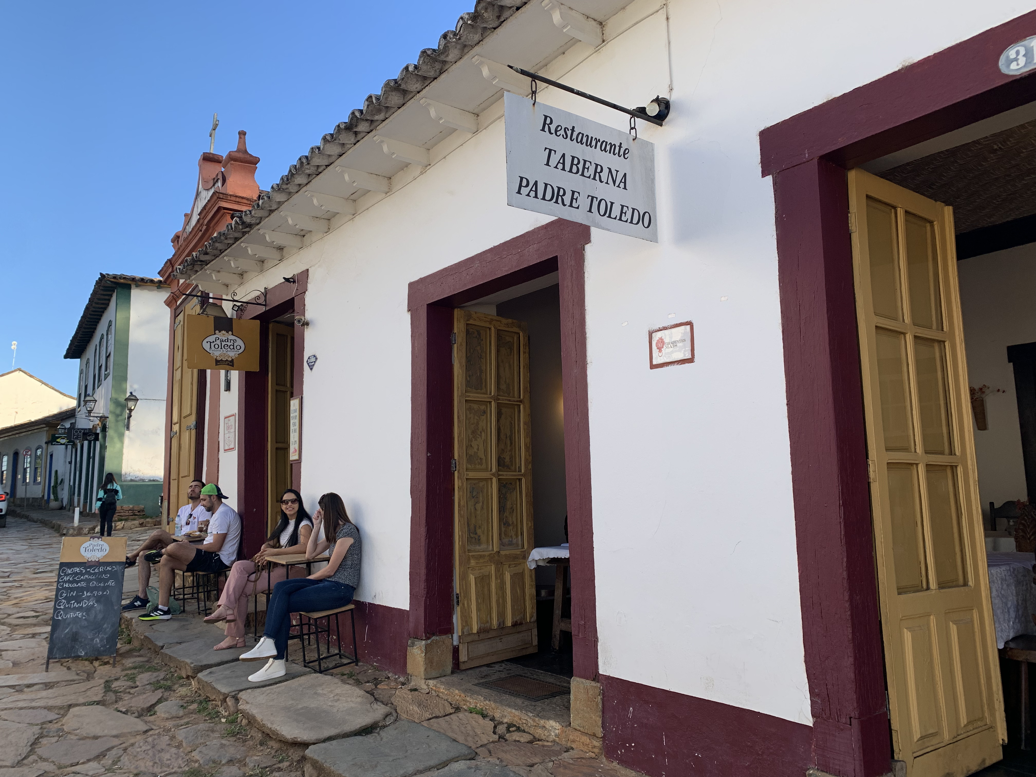 foto da fachada do restaurante Padre Toledo mostrando placa do estabelecimento e a porta de entrada com o contorno vermelho