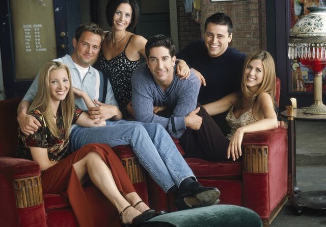 Elenco de Friends posando no cenário do Central Perk, o café que os personagens frequentavam na série.