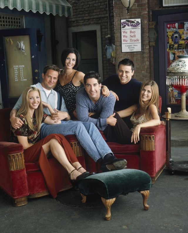 Elenco de Friends posando no cenário do Central Perk, o café que os personagens frequentavam na série.